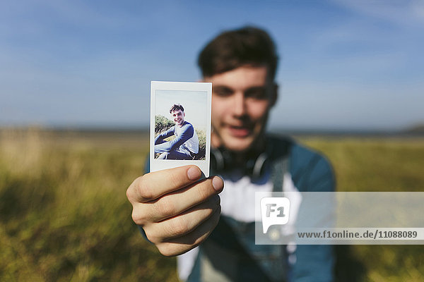 Young man showing polaroid of himself