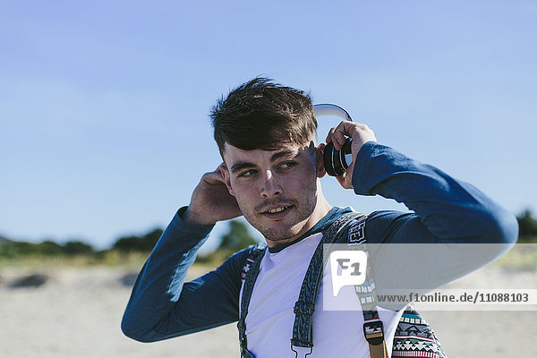 Portrait of young man with headphones on the beach