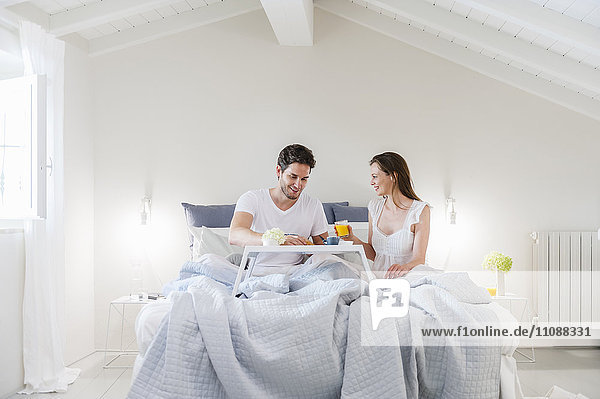 Couple in bed with breakfast tray