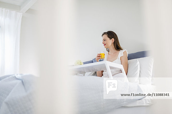Woman sitting in bed with breakfast tray