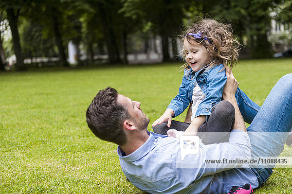 Vater und Tochter spielen auf einer Wiese im Park
