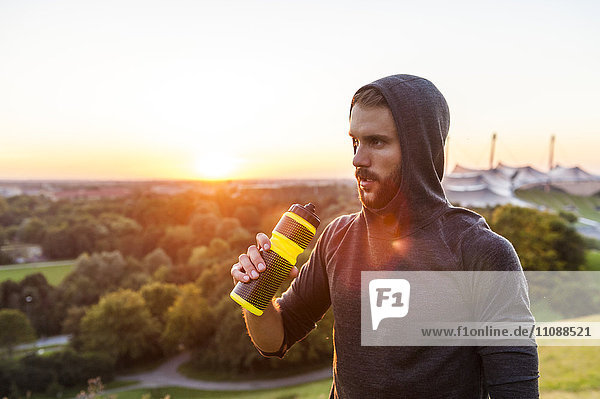 Sportler mit Flasche bei Sonnenuntergang