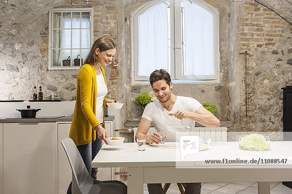 Couple in kitchen eating fruit salad