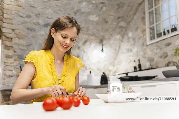 Frau in der Küche schneidet Tomaten
