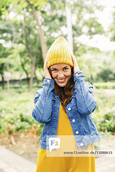 Porträt einer lächelnden jungen Frau mit gelber Mütze