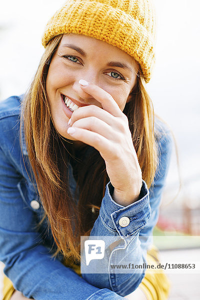 Porträt einer lachenden jungen Frau mit gelber Mütze