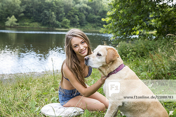 Junge Frau mit ihrem Hund am Ufer des Sees