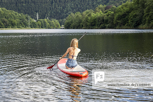 Young woman paddle boarding in a lake