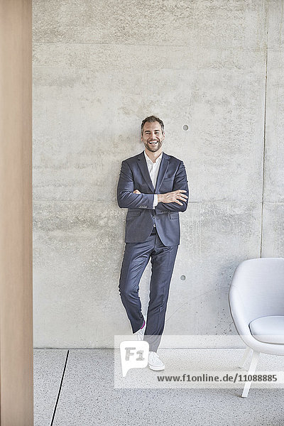 Laughing businesssman standing at concrete wall