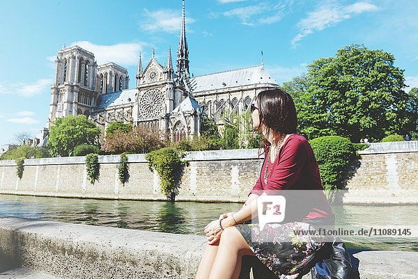 Frankreich  Paris  Frau sitzt am Ufer der Seine vor der Notre-Dame de Paris