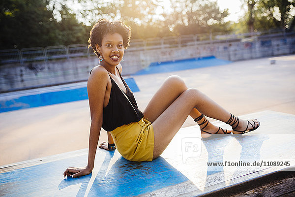 Portrait of smiling young woman sitting in a skatepark