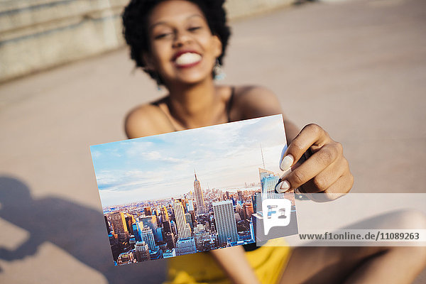 Glückliche Frau zeigt Postkarte von New York City