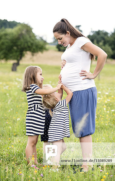 Schwangere Frau im Park mit kleinen Mädchen