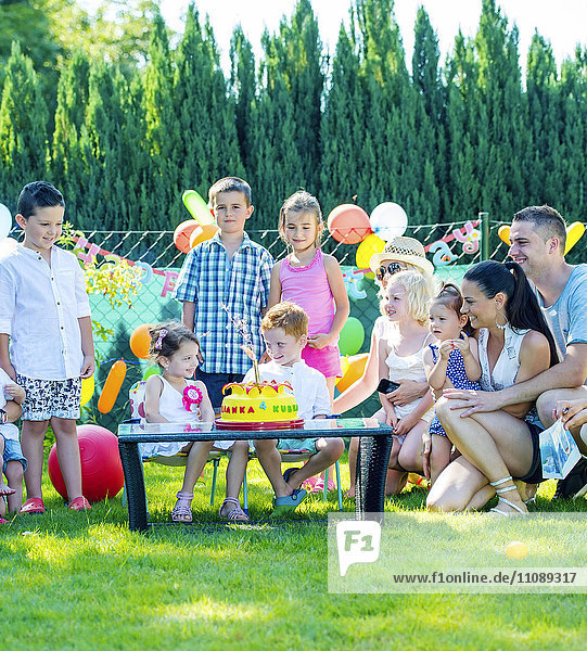 Children celebrating birthday party with friends and family in the garden