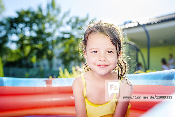 Portrait of smiling little girl sitting in paddling pool