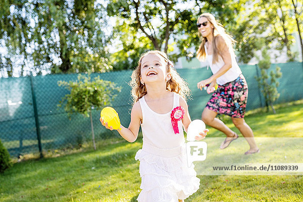 Kleines Mädchen beim Spaß mit Wasserbomben im Garten