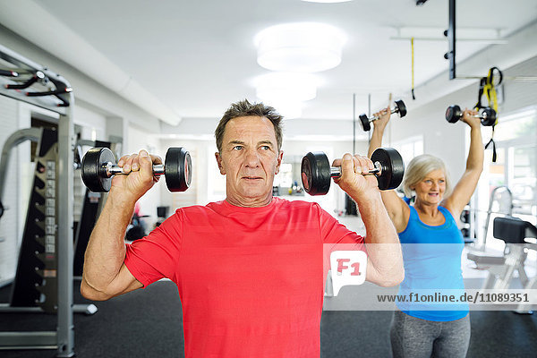 Senior man and mature woman working out in fitness gym