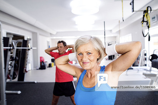 Mature woman and senior man doing gymnastics in fitness gym