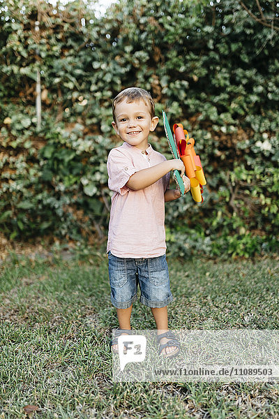 Boy holding home-made cardboard flower in garden