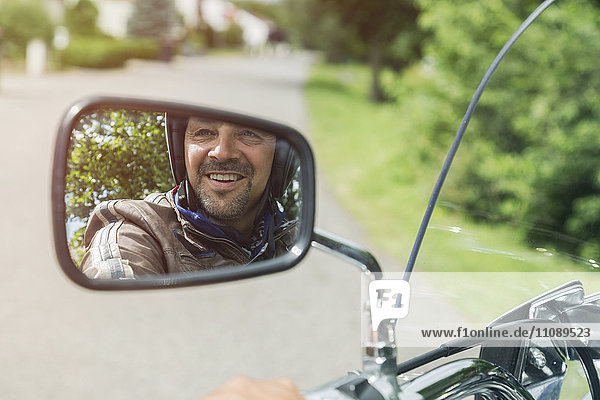 Reflection of smiling man in mirror of motorbike