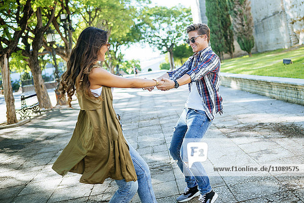 Fröhliches junges Paar tanzt zusammen auf dem Bürgersteig