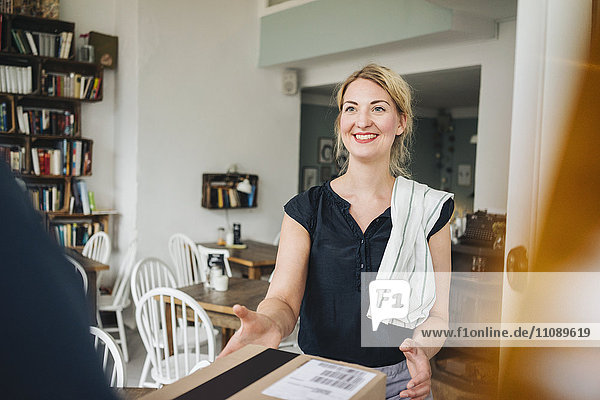 Lächelnde Frau empfängt Paket in einem Cafe