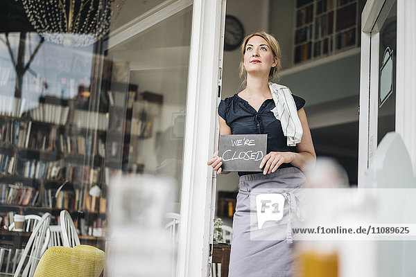 Woman in a cafe holding closed sign