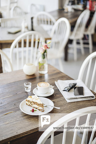Handy  Sonnenbrille  Kuchen und Tasse Kaffee auf dem Tisch im Cafe