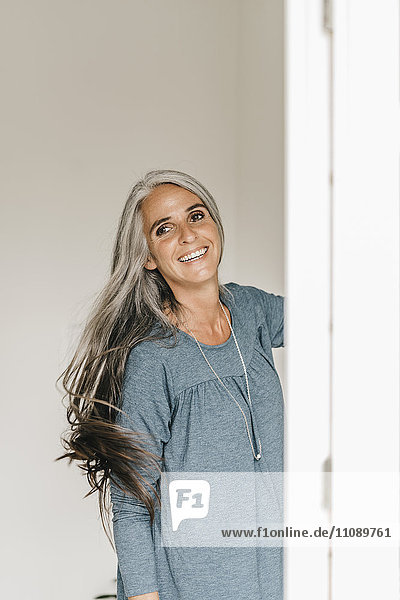 Porträt einer lächelnden Frau  die ihr langes graues Haar wirft.