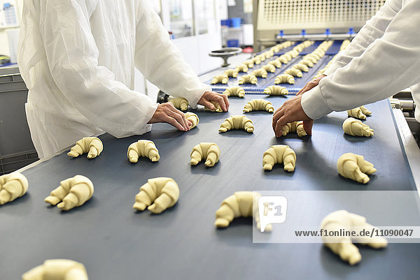 Arbeiter an der Produktionslinie einer Backfabrik mit Croissants
