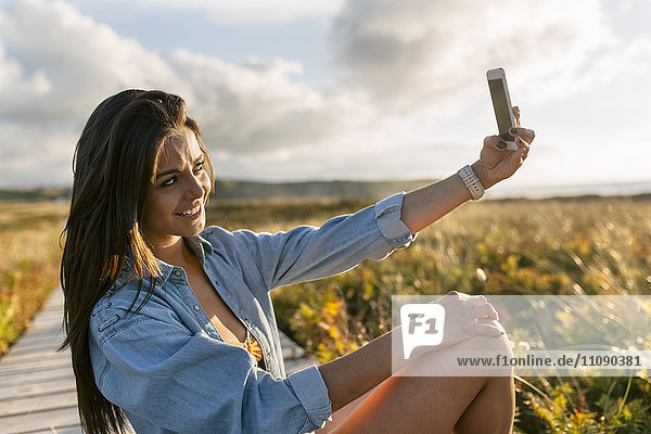 Spanien  Asturien  schöne junge Frau  die einen Selfie an der Strandpromenade macht.