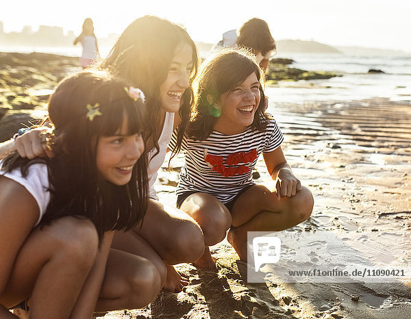 Drei glückliche Mädchen am Strand bei Sonnenuntergang