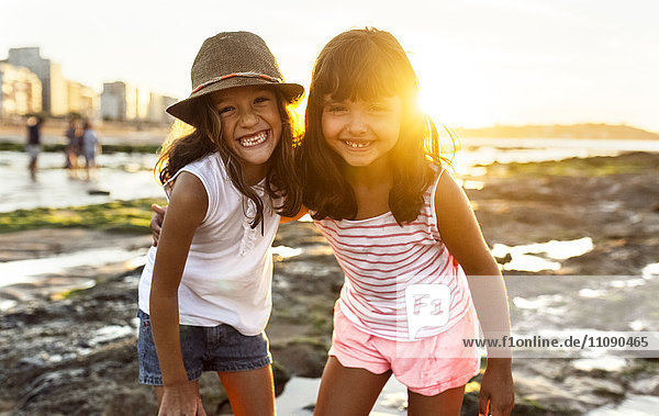 Portrait von zwei lächelnden Mädchen am Strand bei Sonnenuntergang