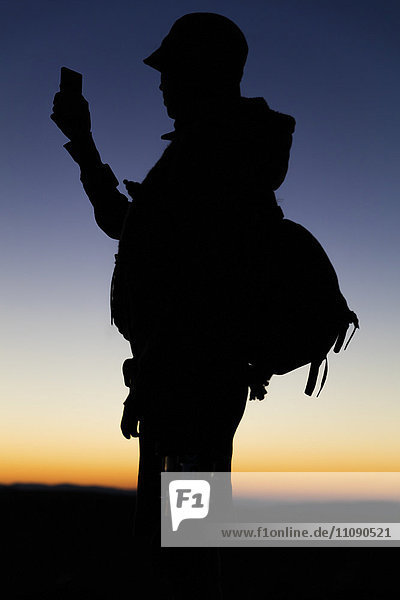 Silhouette des Wanderers beim Blick auf das Smartphone