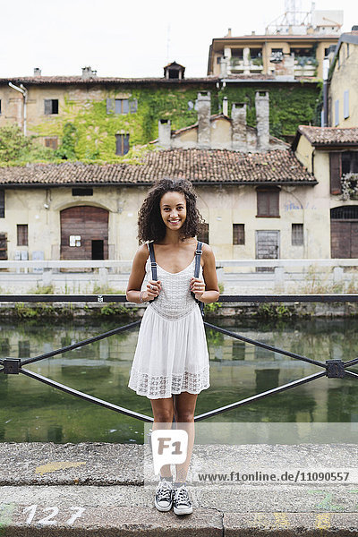 Italien  Mailand  Porträt einer lächelnden jungen Frau mit Rucksack in weißem Sommerkleid