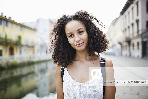 Italy  Milan  portrait of smiling young woman with curly brown hair