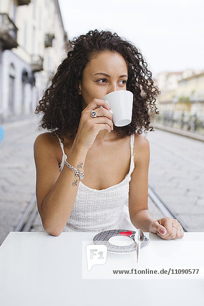 Junge Frau trinkt Kaffee im Straßencafé