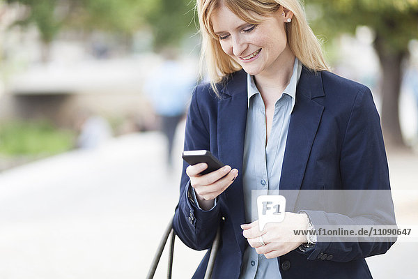 Smiling blond businesswoman looking at smartphone