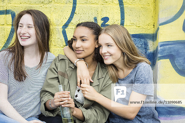 Drei Teenager-Mädchen sitzen vor dem Graffiti