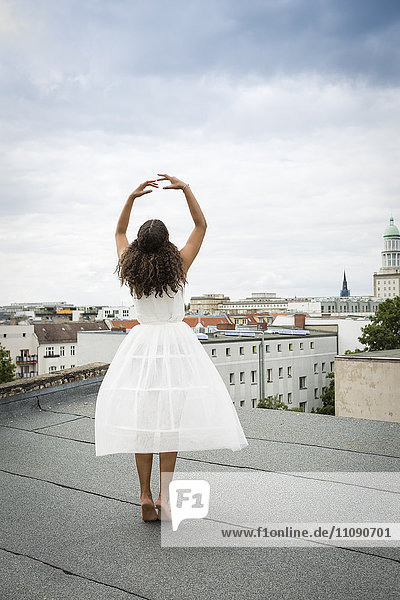 Deutschland  Berlin  Rückansicht einer jungen Balletttänzerin  die auf einem Dach trainiert.