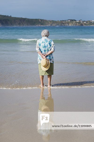 Rückansicht der älteren Frau  die am Strand am Meer steht
