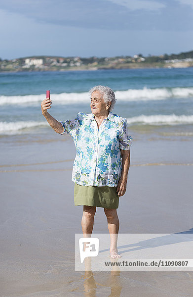 Seniorenfrau  die sich selbst am Strand mitnimmt.