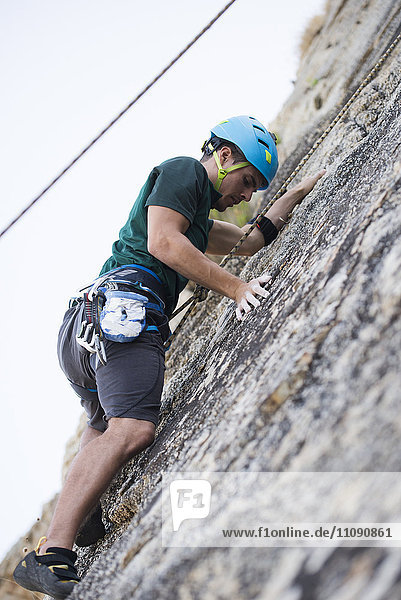 Junger Mann klettert auf eine Felswand