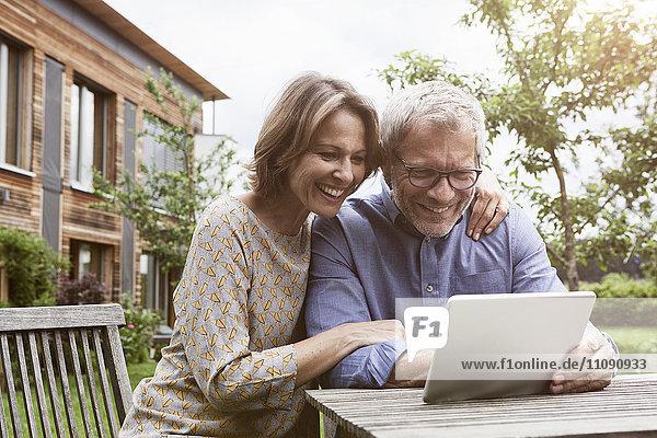 Happy mature couple sharing digital tablet in garden