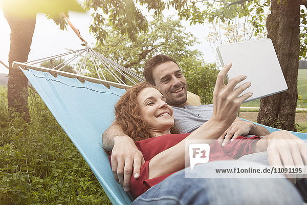 Smiling couple in hammock using tablet
