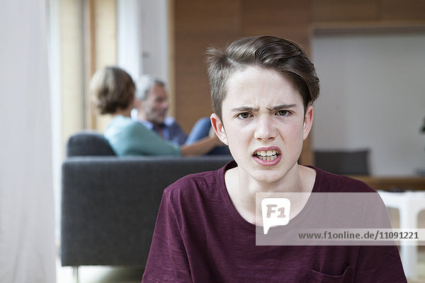 Porträt des wütenden Teenagers zu Hause mit Eltern im Hintergrund