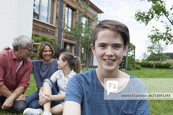 Porträt eines lächelnden Teenagers mit seiner Familie im Garten