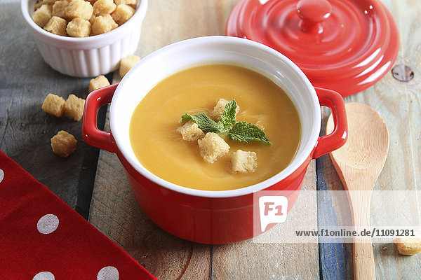 Pot of creamed pumpkin soup with bread cubes