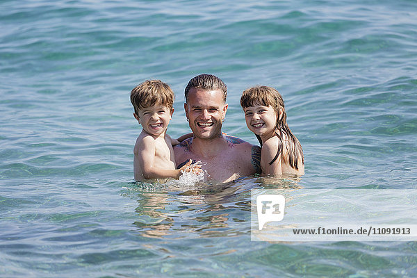 Tätowierter Mann mit seinen Kindern im Meer