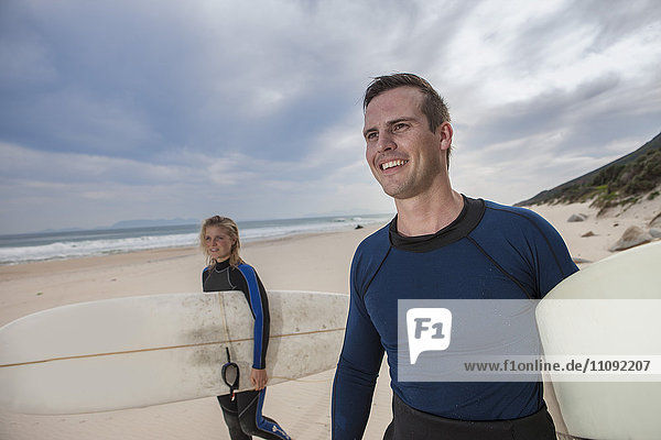 Paar mit Surfbrettern am Strand